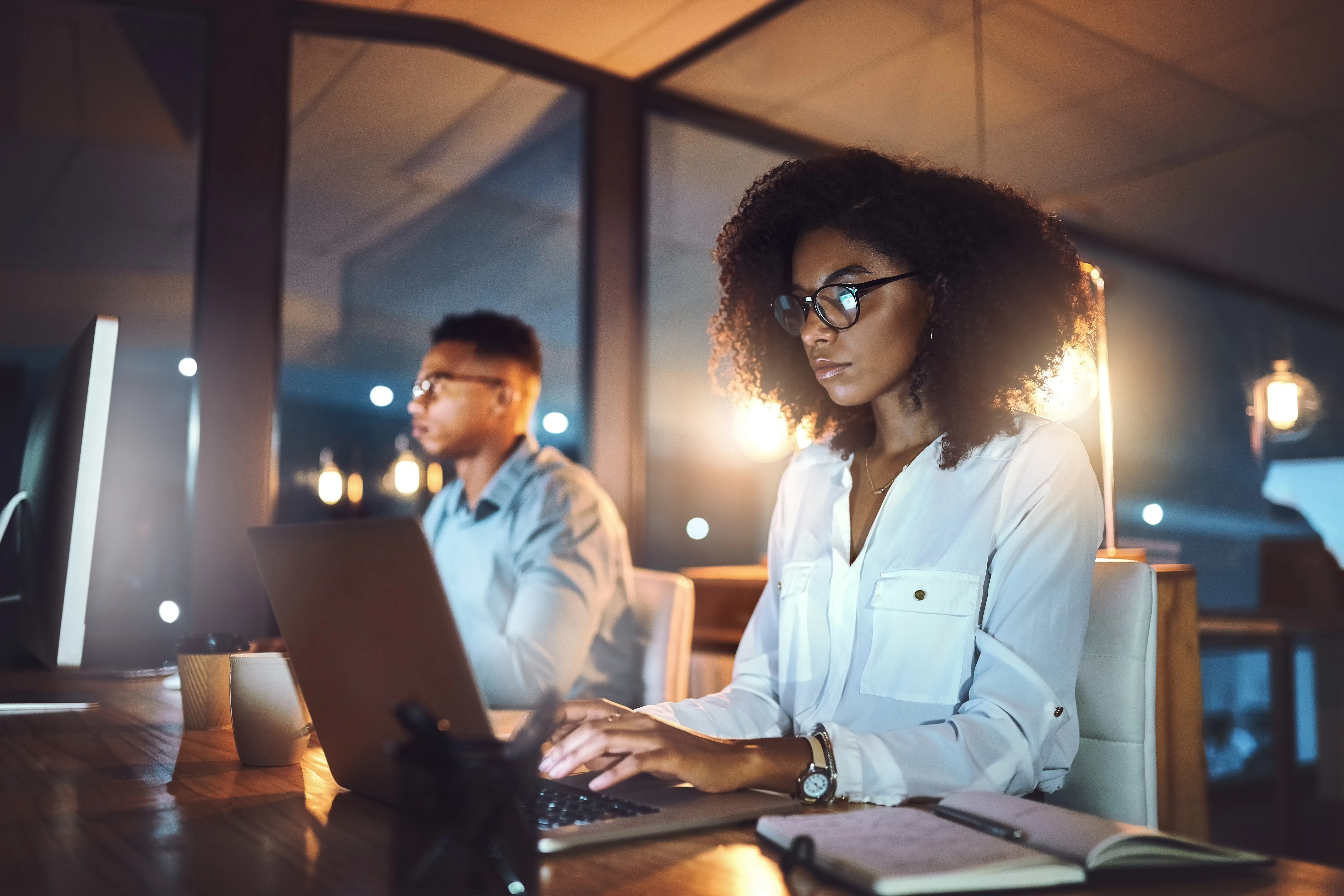 two people working with laptop in blue light