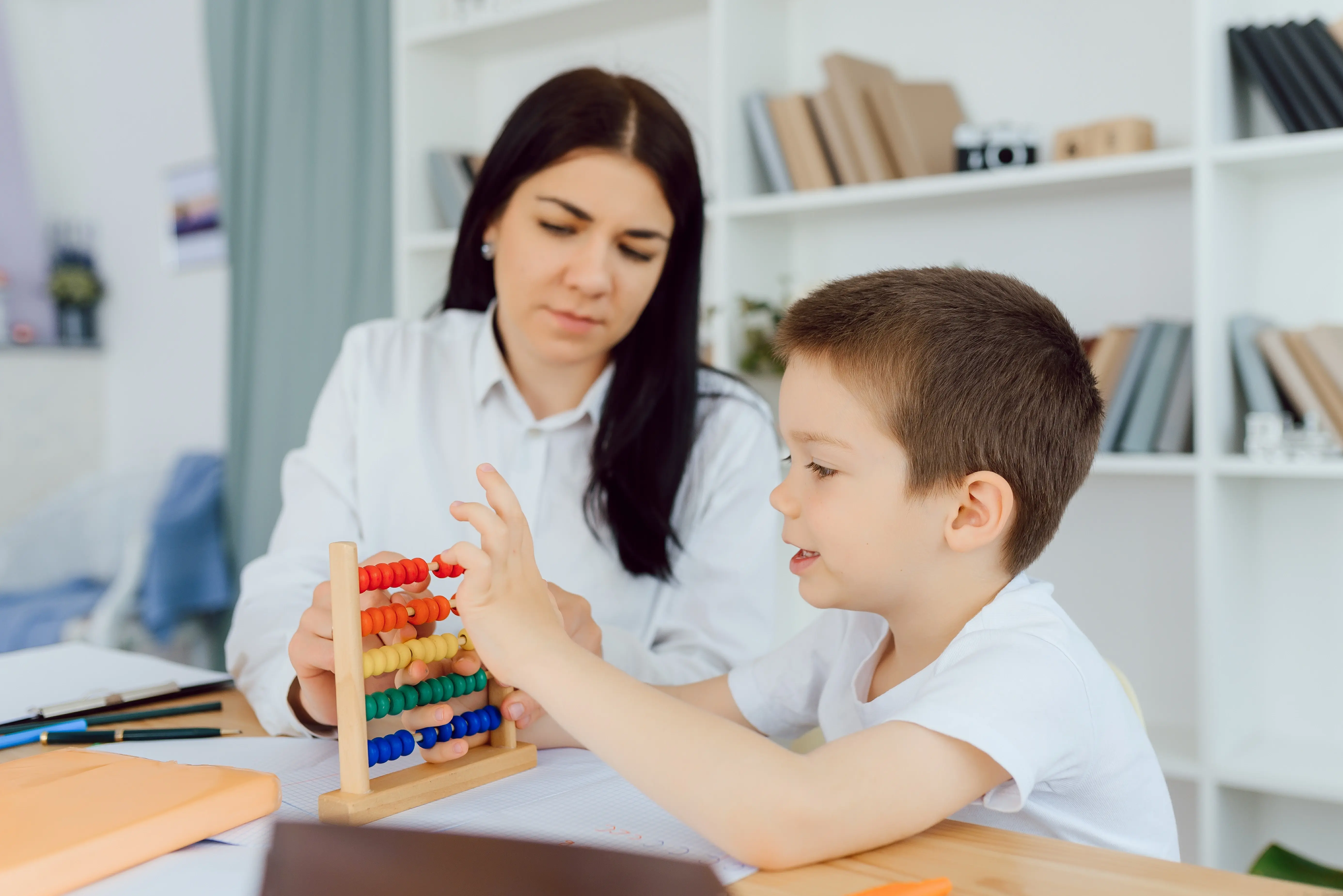 a woman and a child with cognitive delay playing with abacus